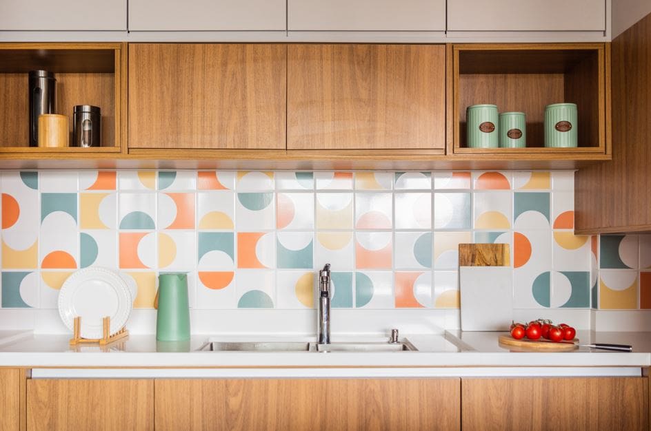 Cozinha com armários de madeira e revestimento colorido com formas geométricas arredondadas.